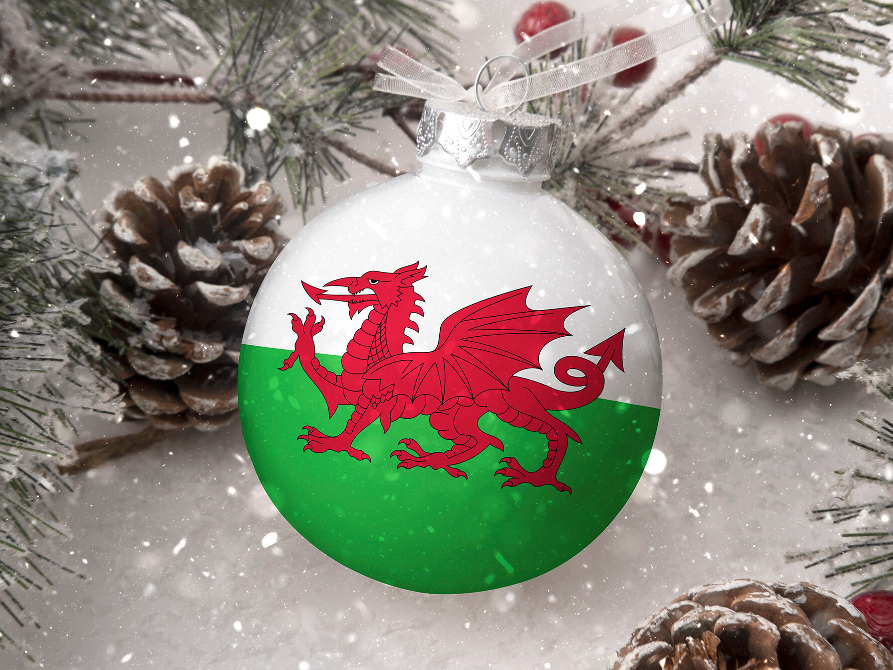 Christmas bauble decorated with the Welsh flag surrounded by pine cones and snow