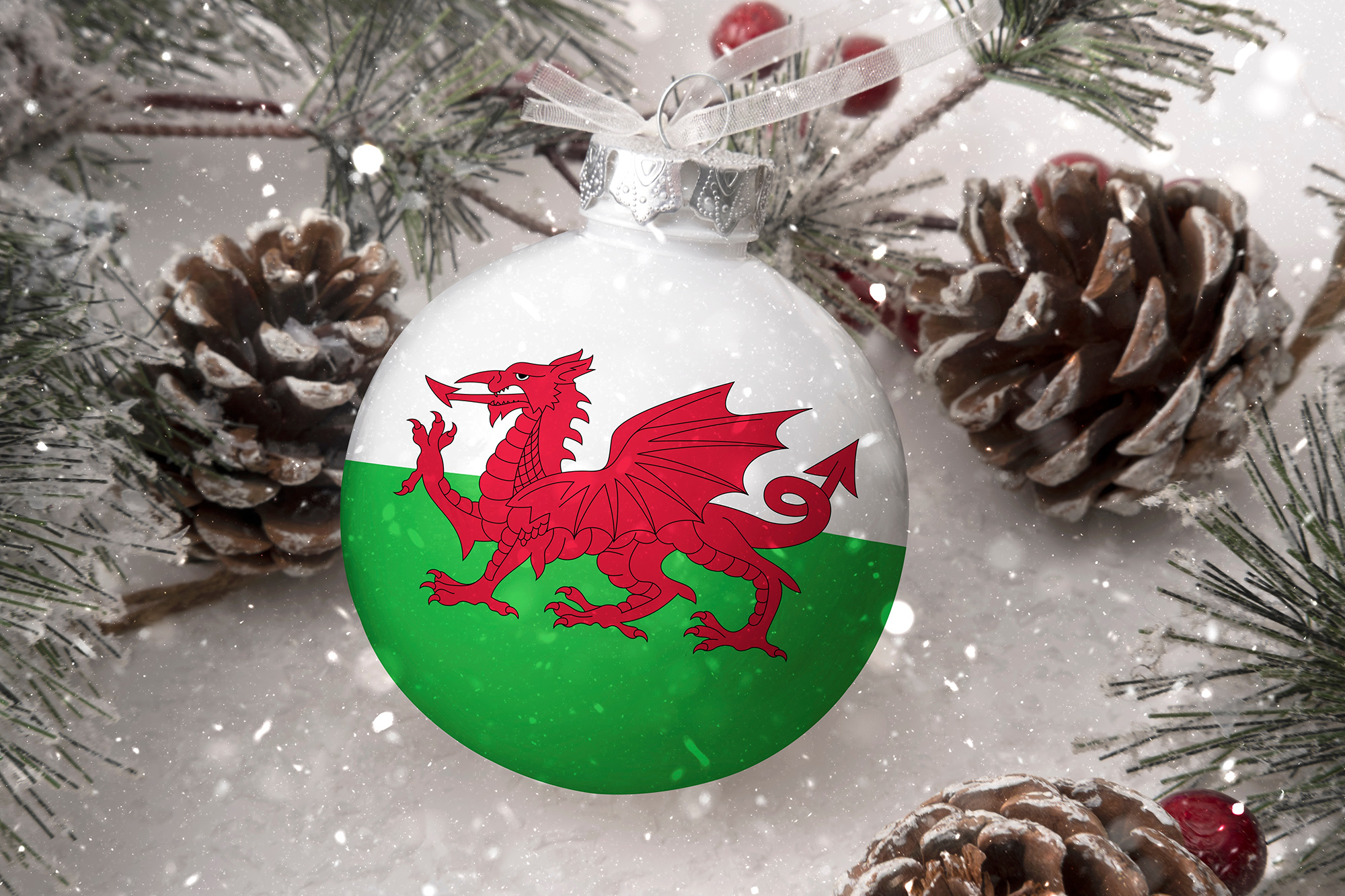 Christmas bauble decorated with the Welsh flag surrounded by pine cones and snow