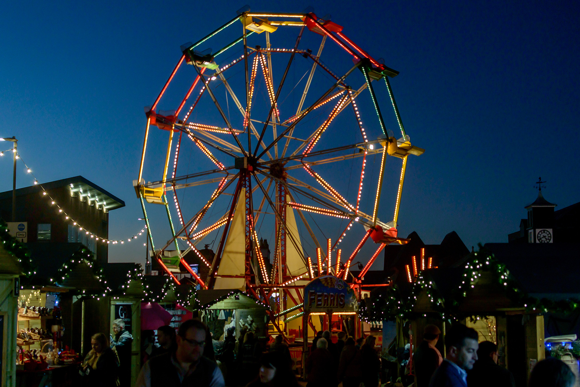 Ferris wheel lit up at night at Gloucester Quays Christmas Market, surrounded by festive stalls and twinkling lights.