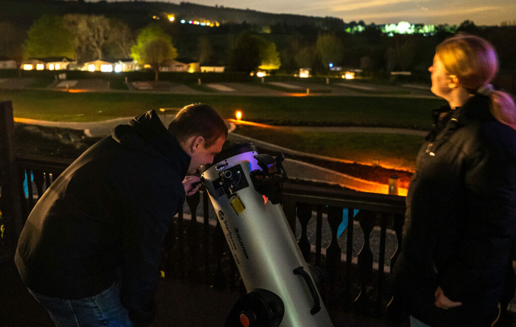 Couple using the telescope on a stargazing holiday at Rockbridge Country Holiday Park.